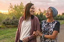 Two people smiling at each other while walking outside,