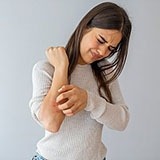 Woman scratching her arm.